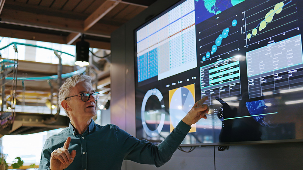 Expert pointing at a wall of monitoring dashboards